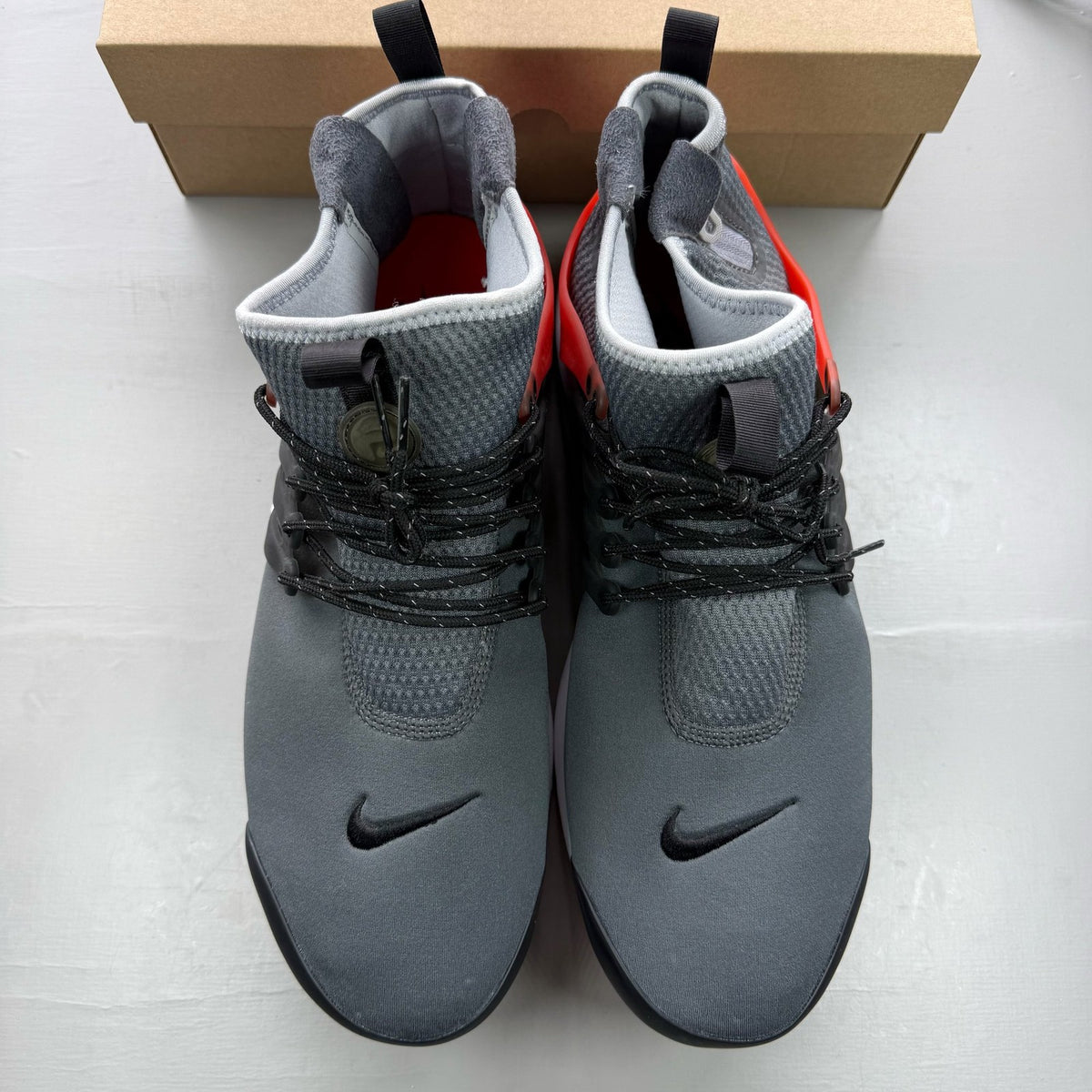 Nike Air Presto grey trainers with black and red accents, featuring a sleek design.