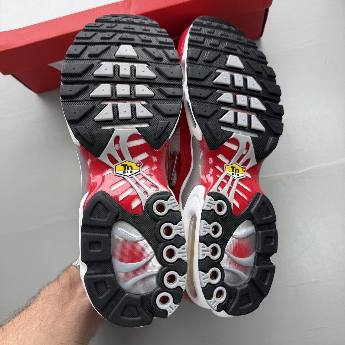 Nike Air Max Plus TN white trainers with university red and grey accents, featuring signature logo.