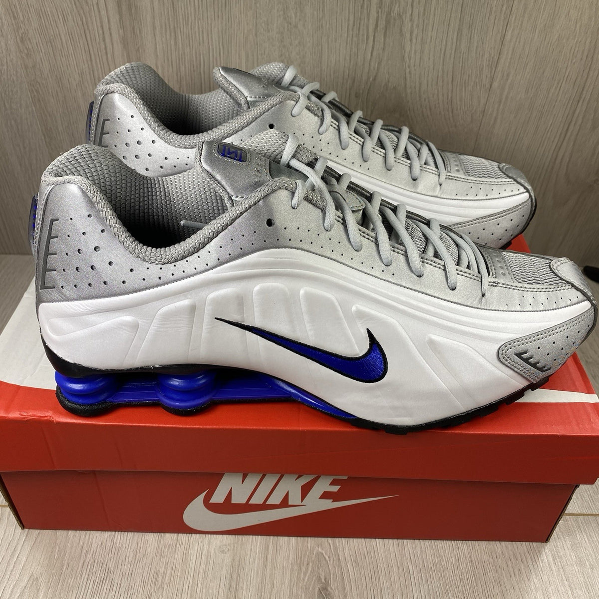 Nike Shox R4 trainers white with blue accents and distinctive Shox cushioning design.