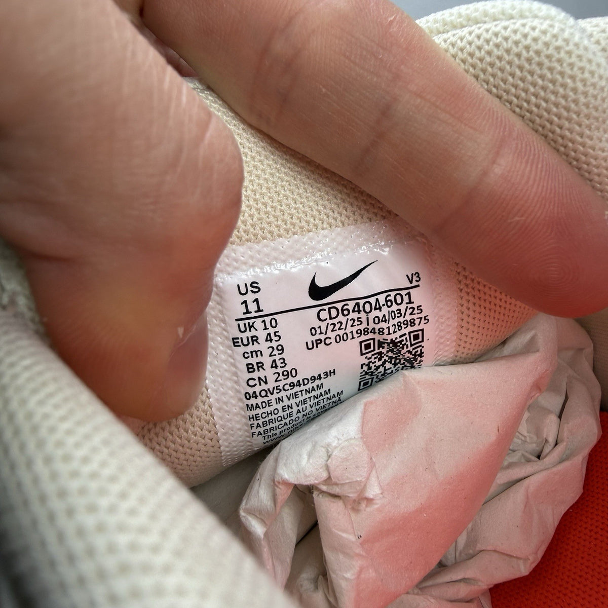 Nike white trainers with bright crimson red accents and soft pearl cream detailing.