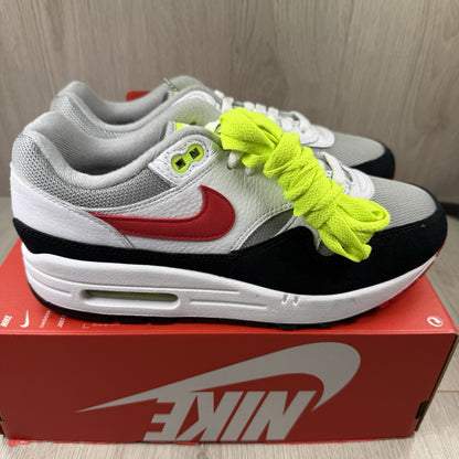 Nike Air Max 1 trainers white with chili volt accents and black detailing.