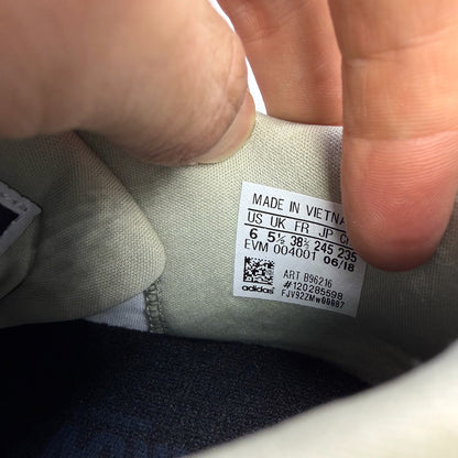Adidas grey trainers with textured upper and distinctive three-stripe logo detail.