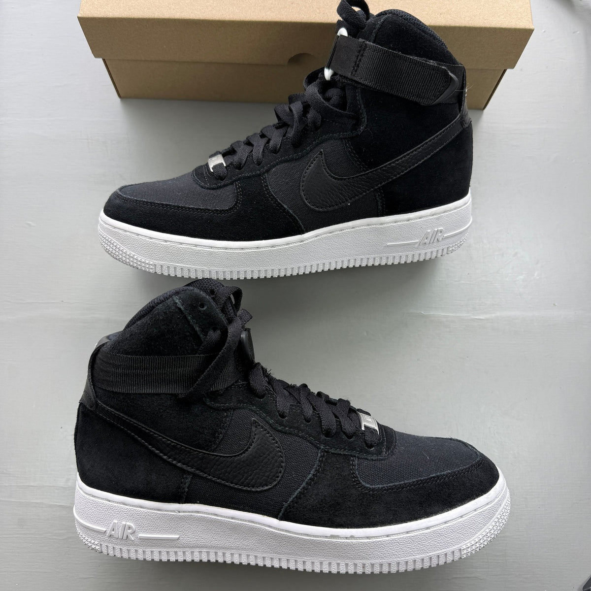 Nike Air Force 1 High black trainers with white logo and durable leather material.