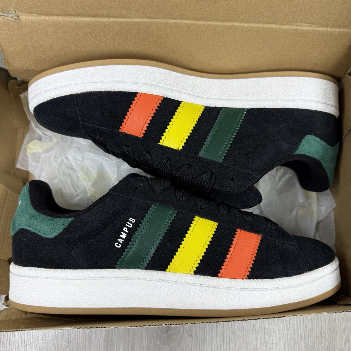 Adidas black trainers with yellow accents and classic three-stripe logo design.