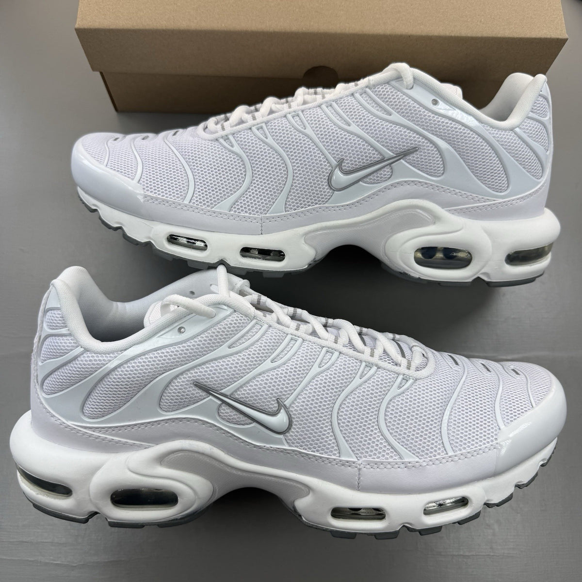 Nike Air Max Plus TN white trainers with grey accents and signature swoosh logo.