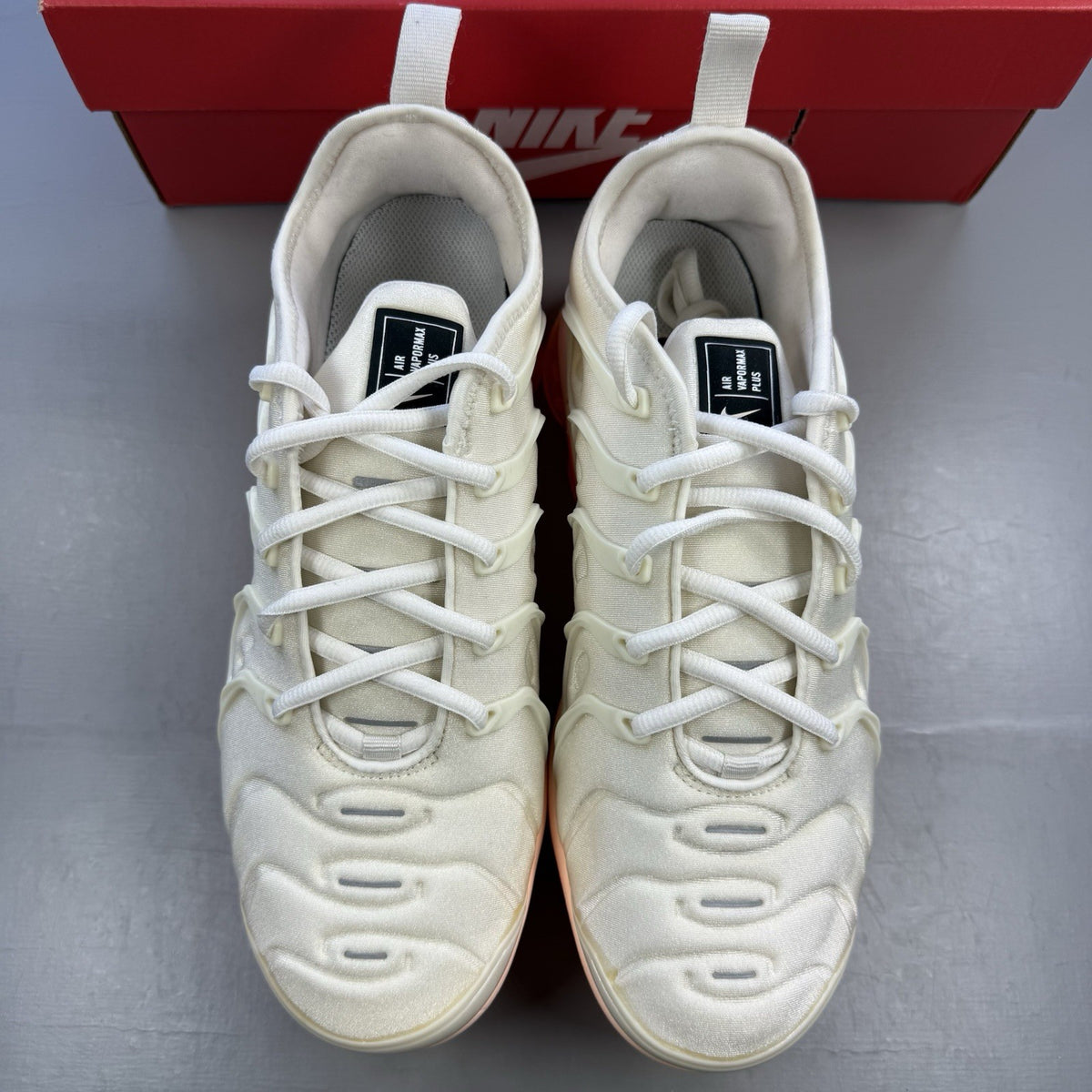 Nike Air VaporMax Plus beige trainers with Phantom Orange accents and distinctive logo.