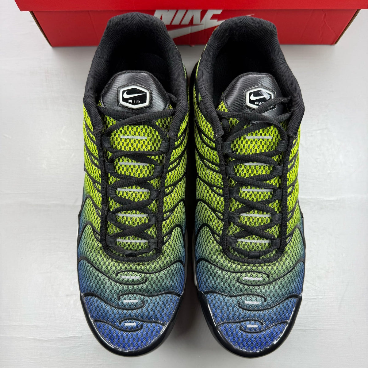 Nike Air Max Plus TN green trainers with black and volt accents, featuring signature logo.