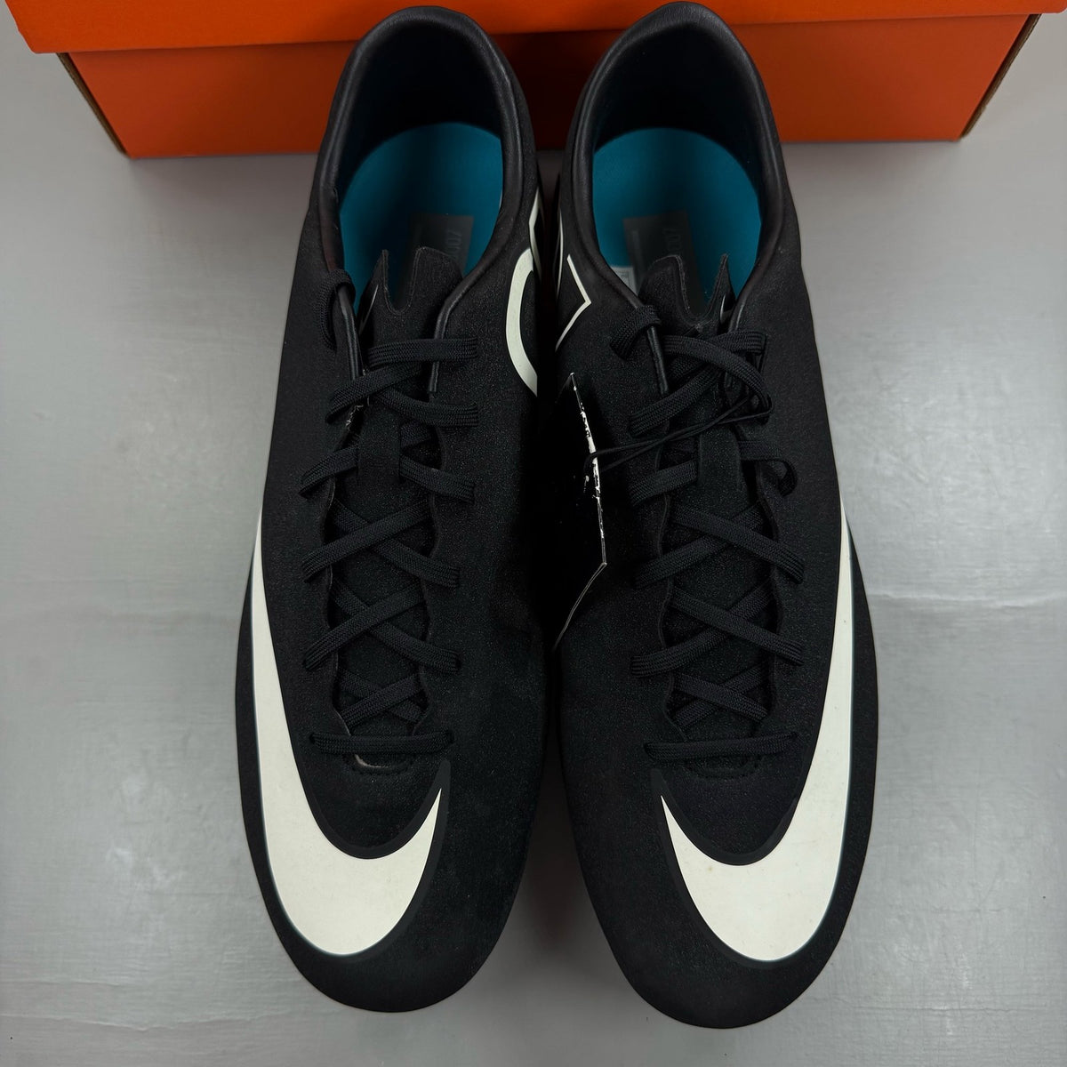Nike black football boots with white Mercurial logo, sleek design, synthetic material.