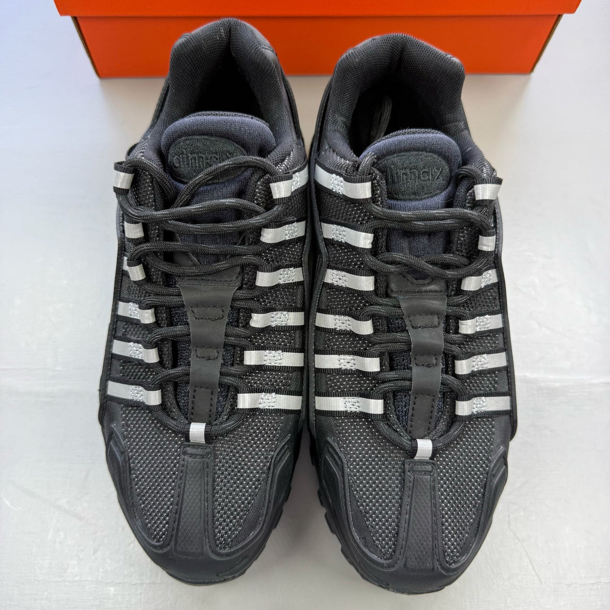Nike Air Max 95 NDSTRKT black trainers with reflective detailing and logo accents.