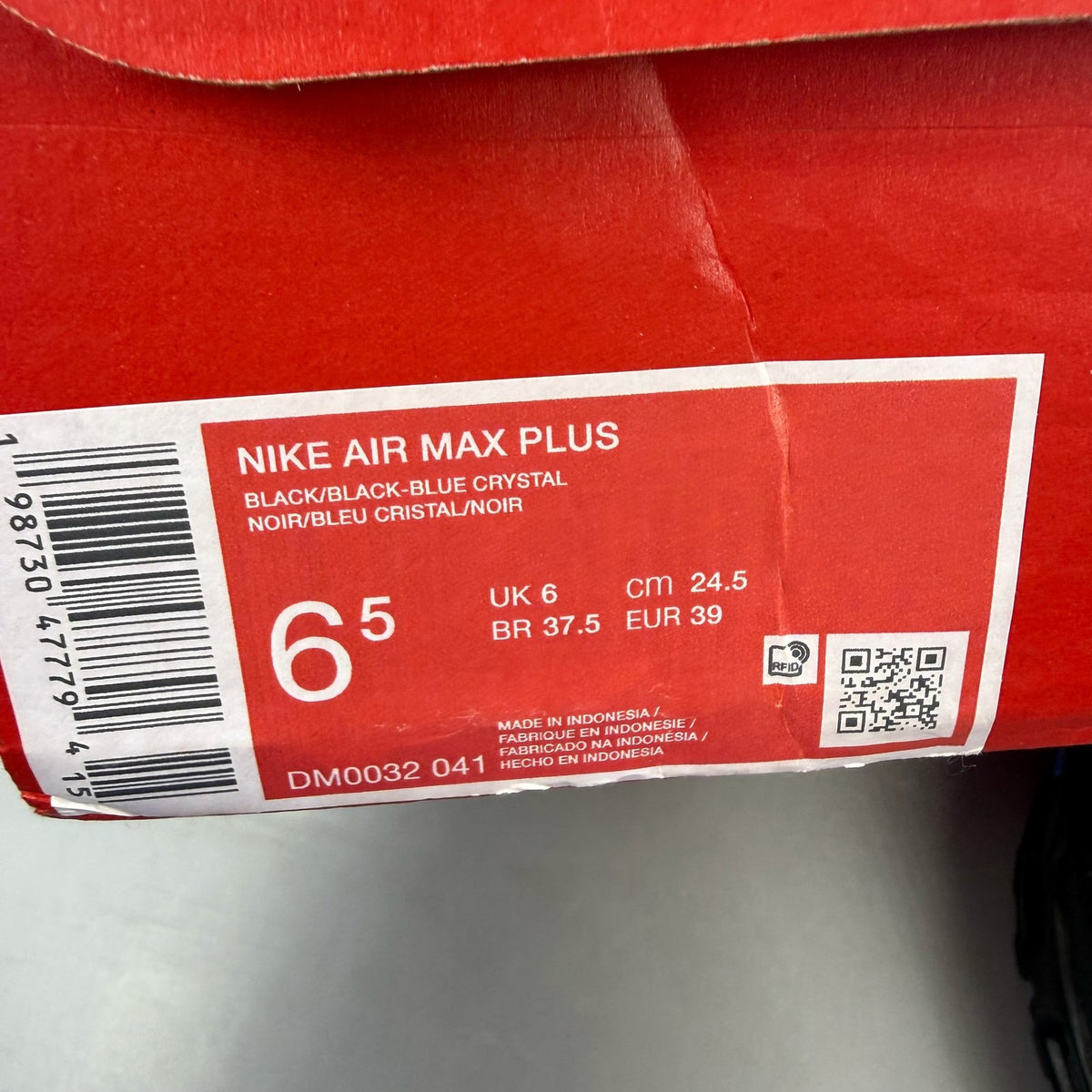 Nike Air Max Plus TN black trainers with blue accents and signature swoosh logo.