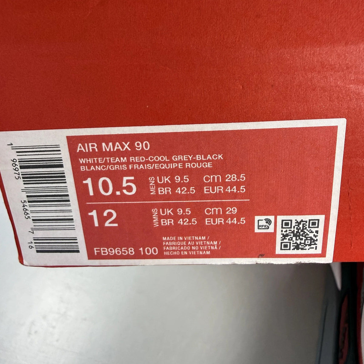 Nike Air Max 90 grey trainers with red accents and gum sole, featuring logo details.