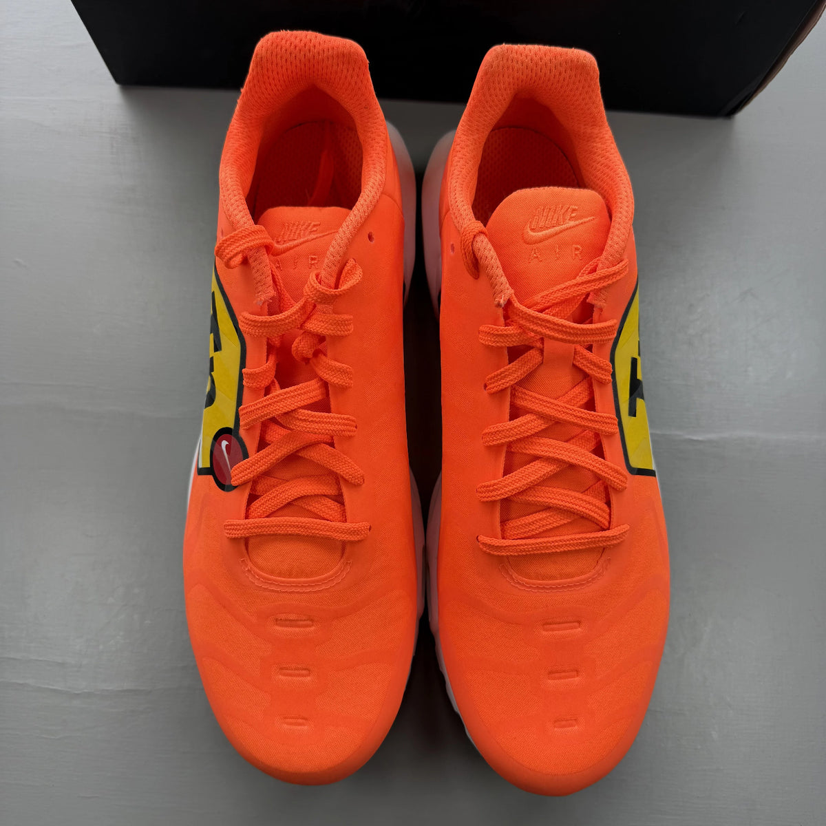 Nike Air Max Plus trainers total orange with large logo and mesh material.
