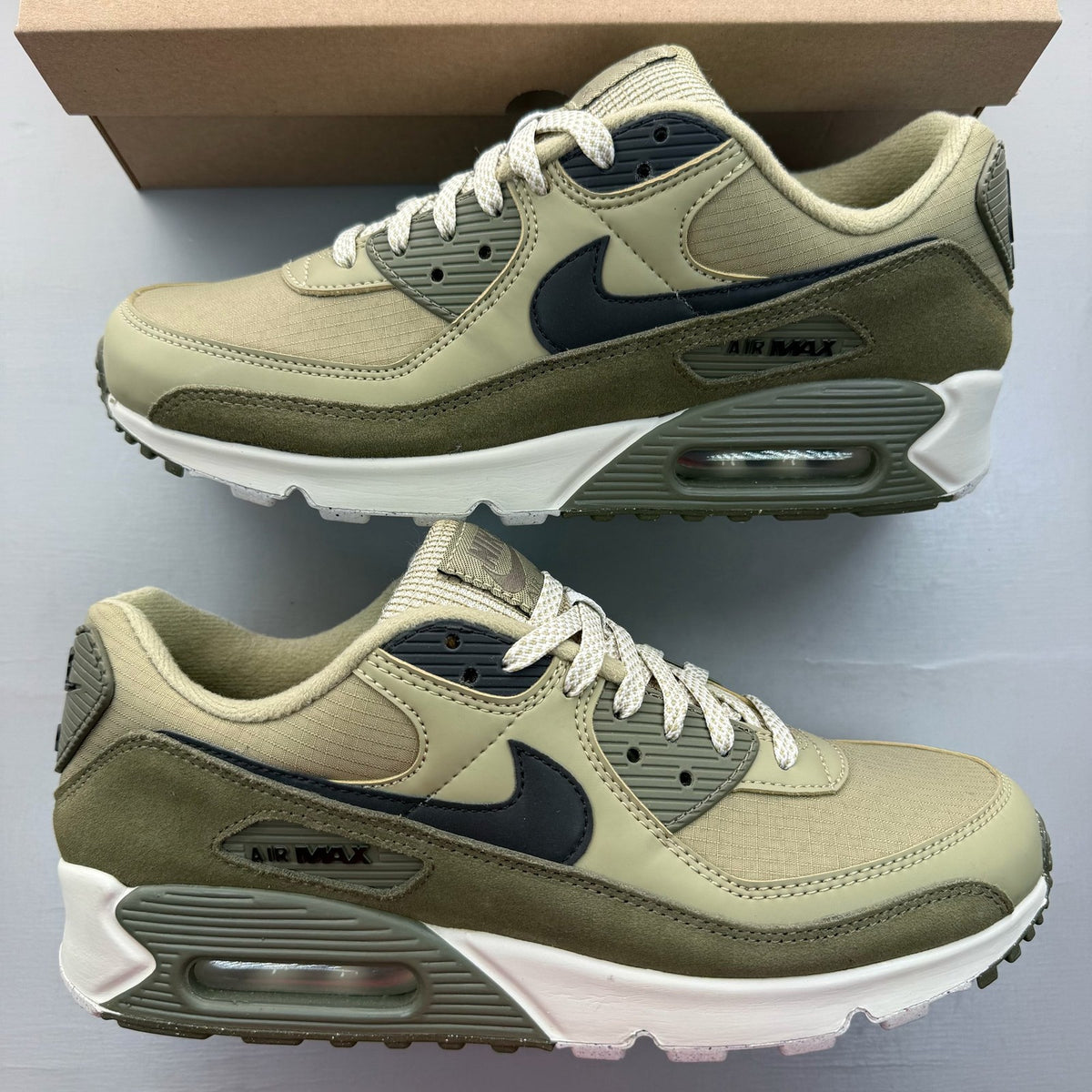 Nike Air Max 90 neutral olive green trainers with black accents and logo details.