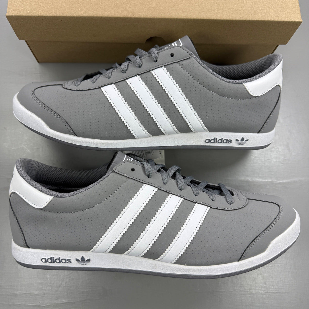 Adidas grey deck shoes with white accents and classic logo detailing.