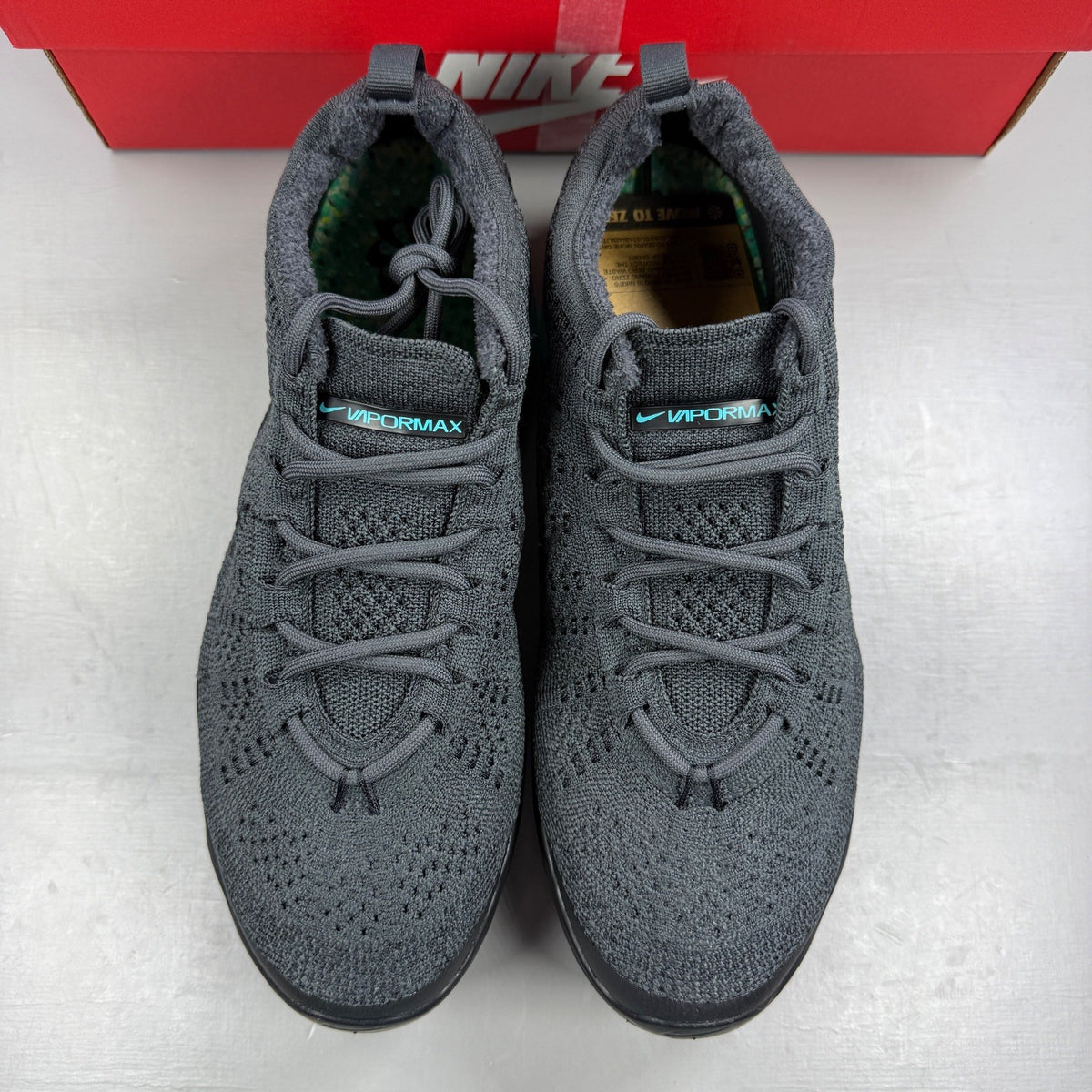 Nike athletic shoes grey Flyknit upper with Air VaporMax sole and logo detail.