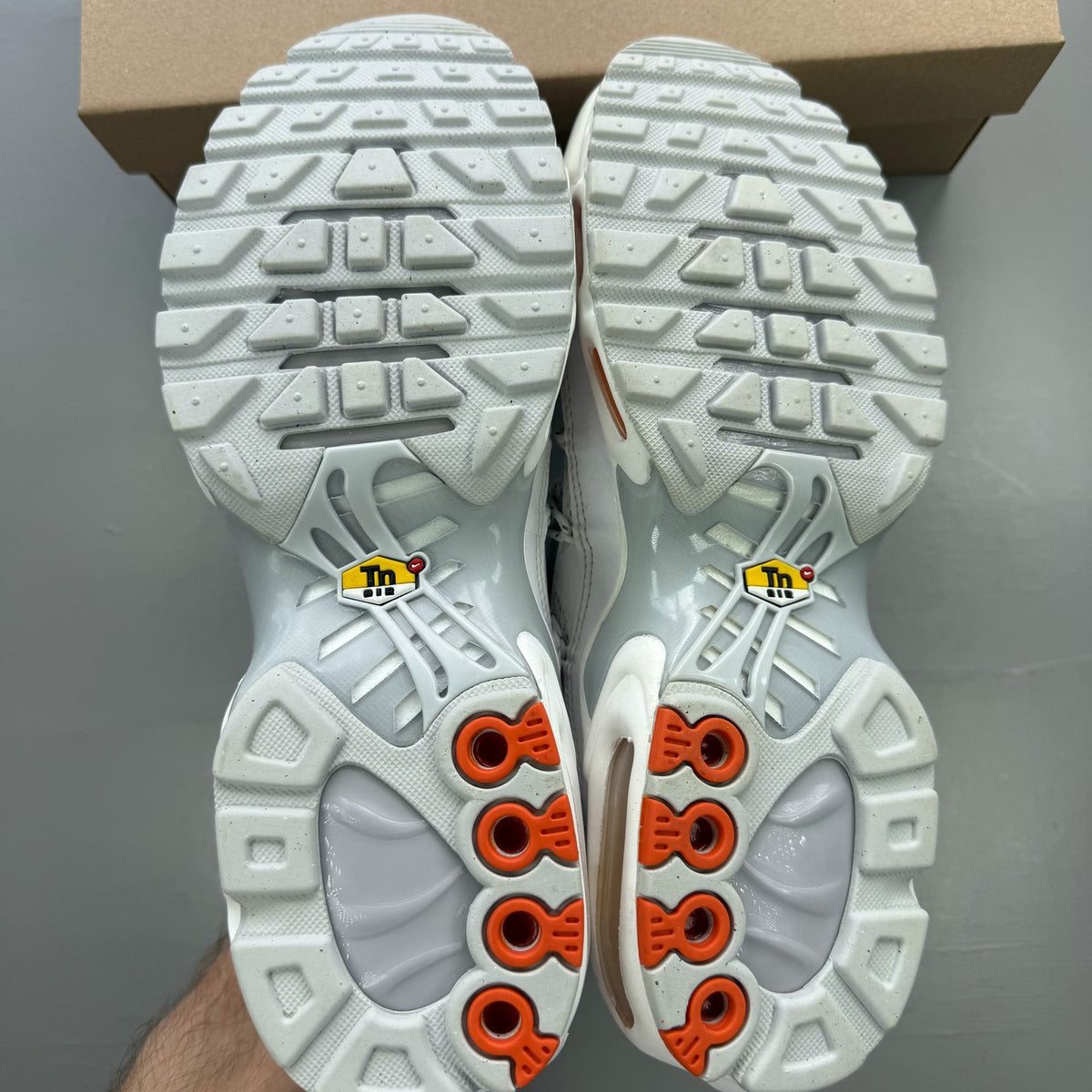 Nike footwear white trainers with orange accents and distinctive Air Max Plus TN design.
