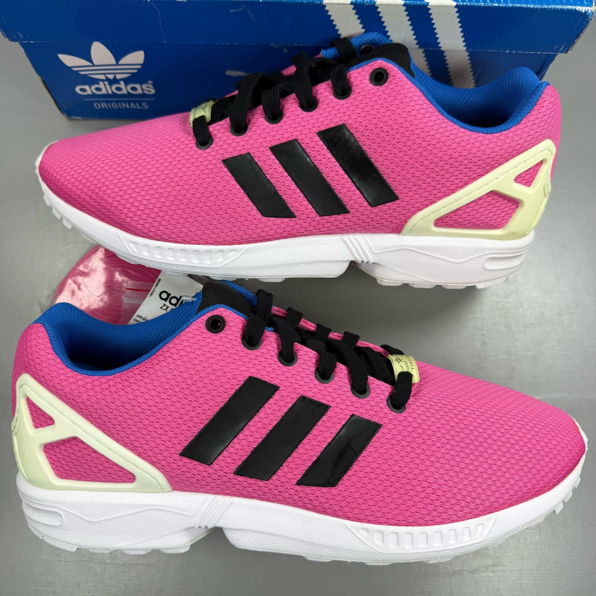 Adidas ZX Flux trainers in shock pink with black and blue accents, mesh upper.