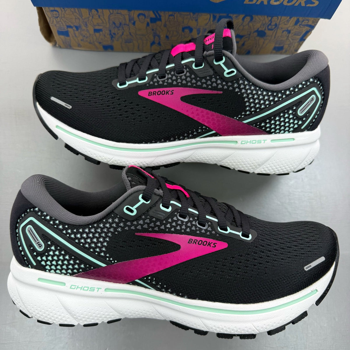Brooks black trainers with white and pink accents, featuring logo and breathable mesh material.