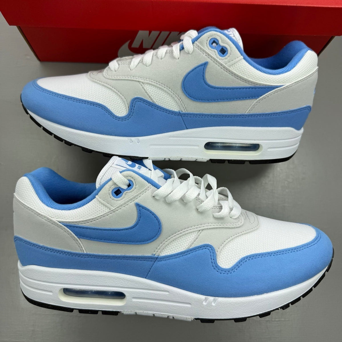 Nike Air Max 1 blue trainers with white accents and UNC logo detailing.