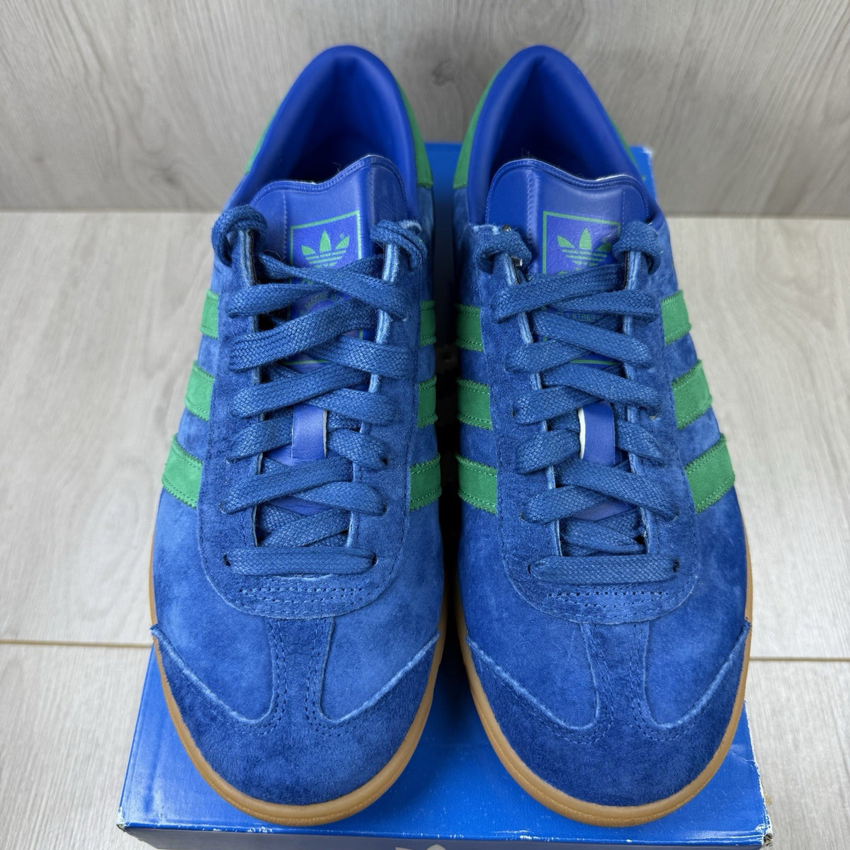 Adidas blue trainers with gum sole and iconic three-stripe logo design.