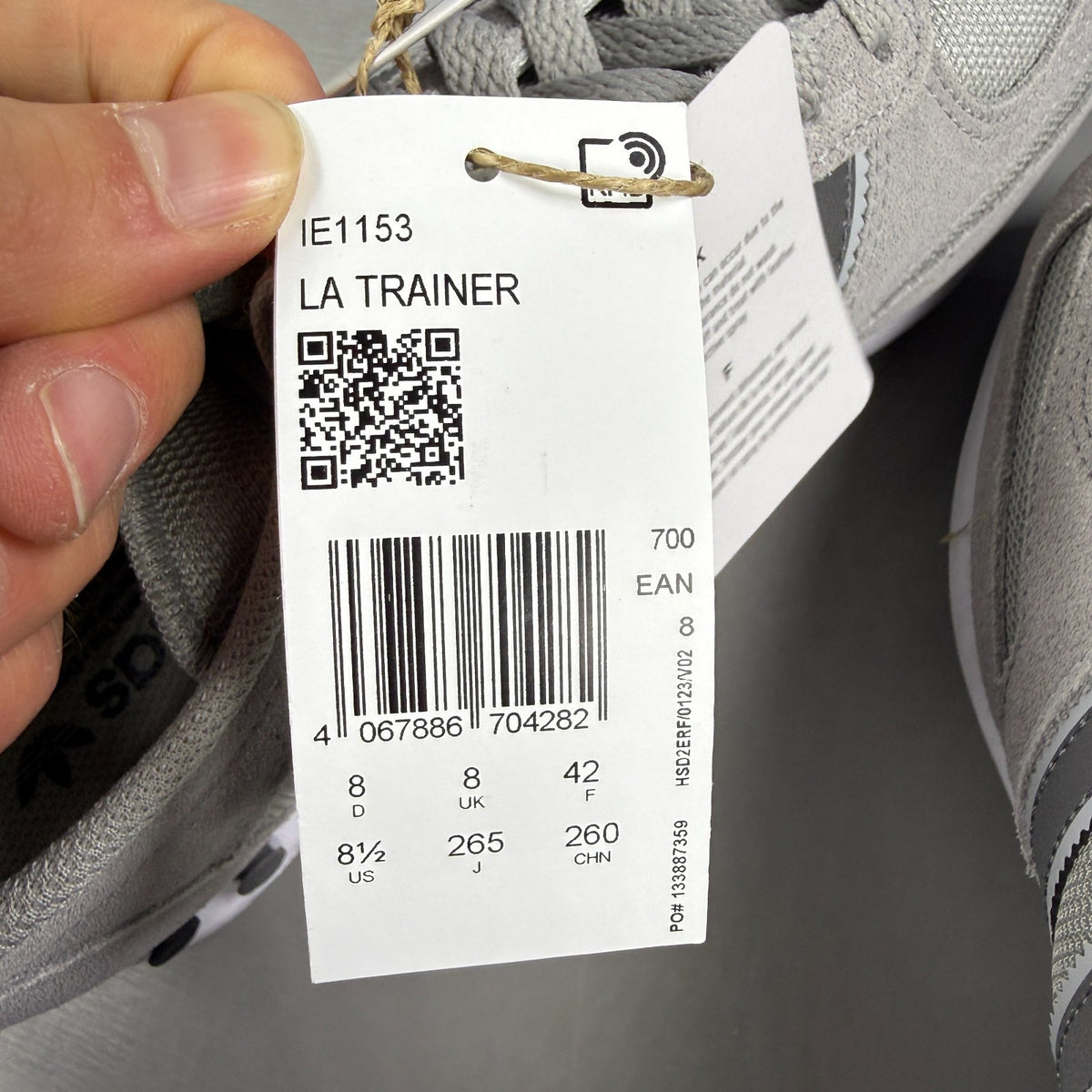 Adidas grey athletic shoes with white accents and classic three-stripe logo.