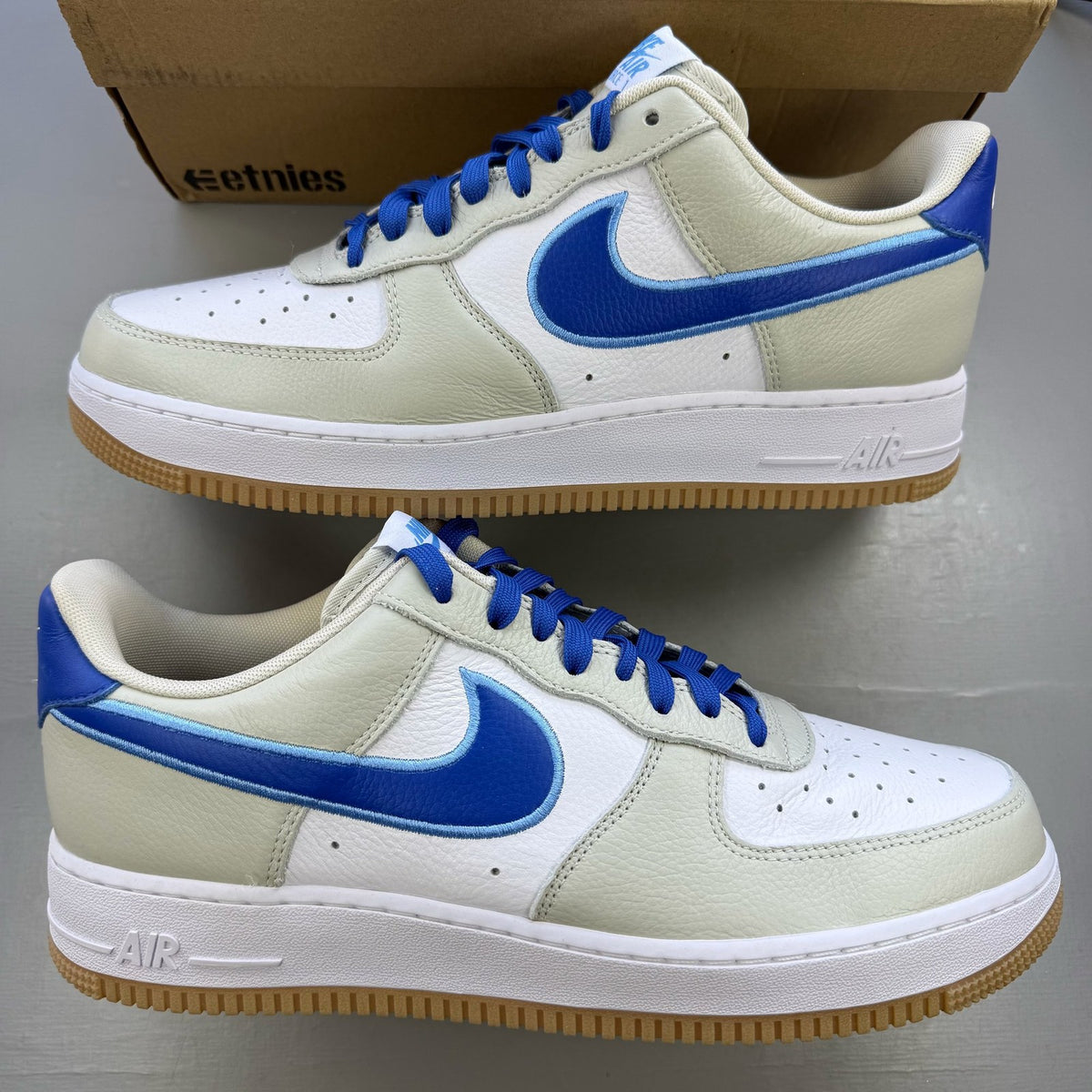 Nike Air Force 1 low trainers white with blue accents and gum sole.