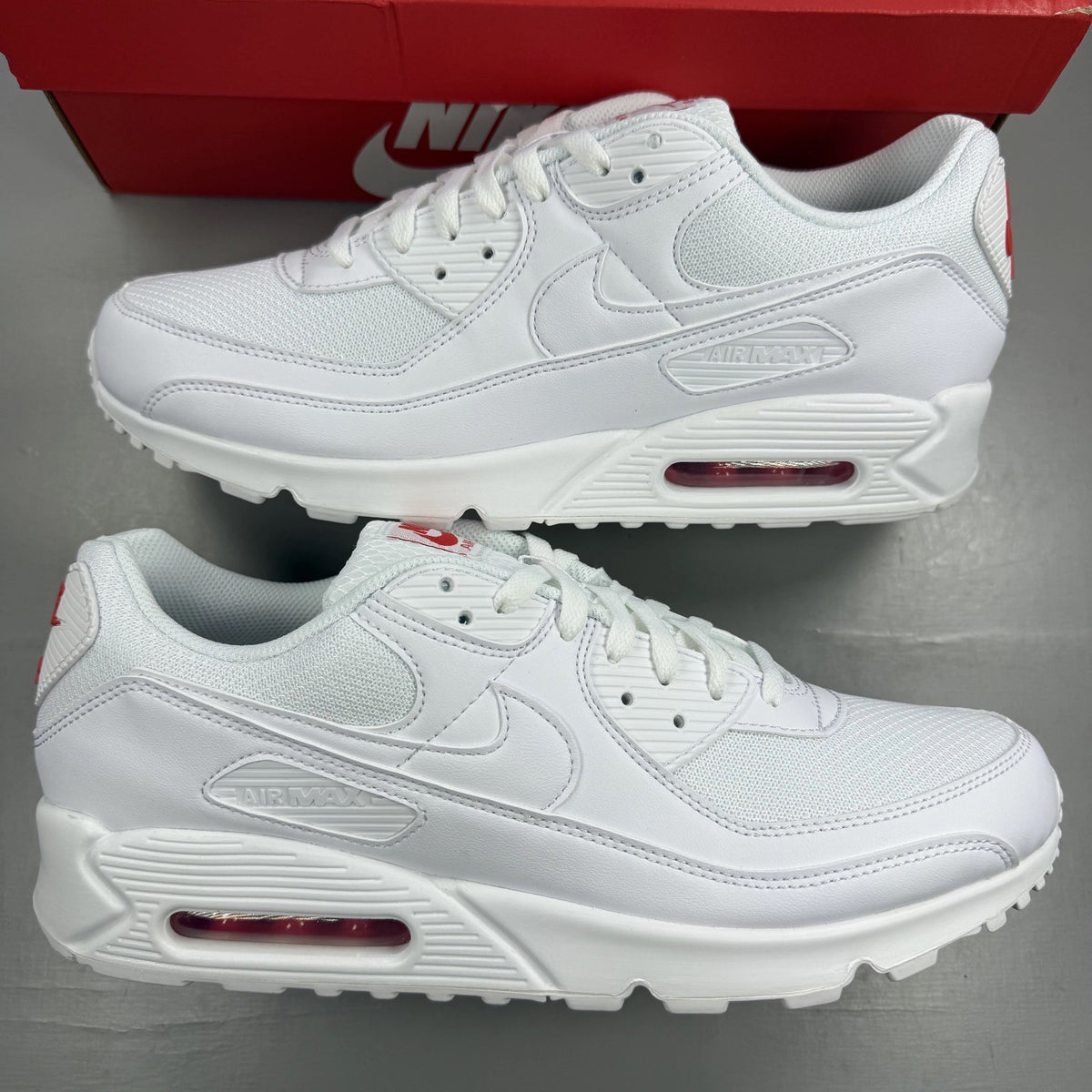 Nike Air Max 90 white trainers with light crimson accents and signature swoosh logo.