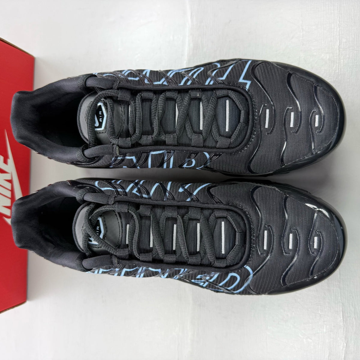 Nike Air Max Plus TN Tuned black trainers with grey accents and signature logo.