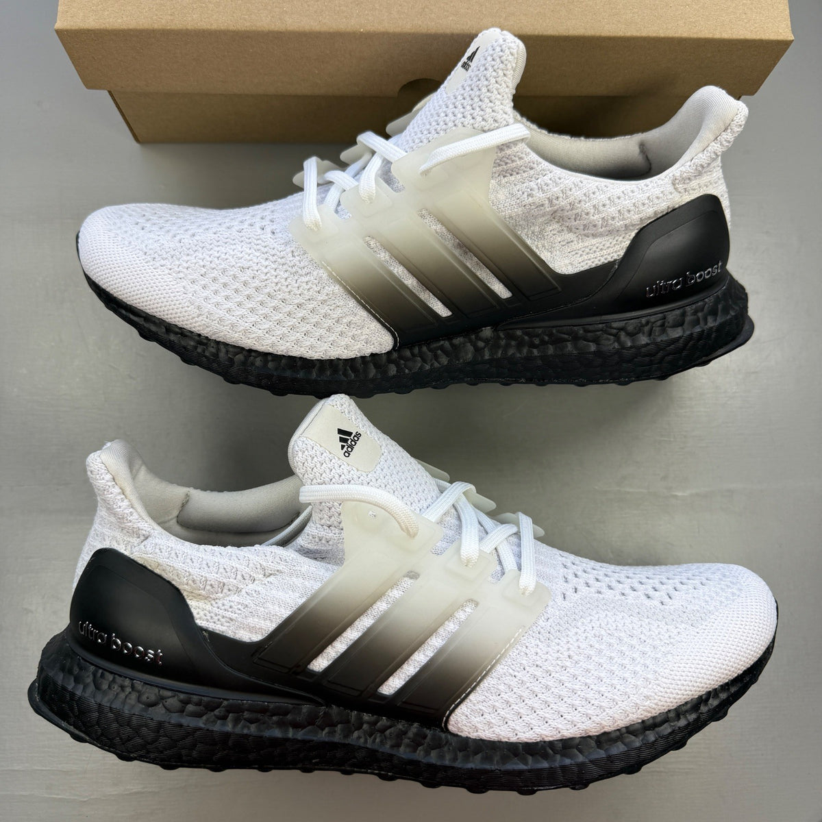 Adidas running shoes white with black accents and Boost cushioning technology.