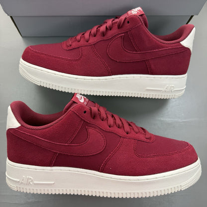 Nike Air Force 1 trainers red suede with white accents and logo detail.