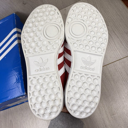 Adidas red trainers with white stripes and logo, classic suede material.