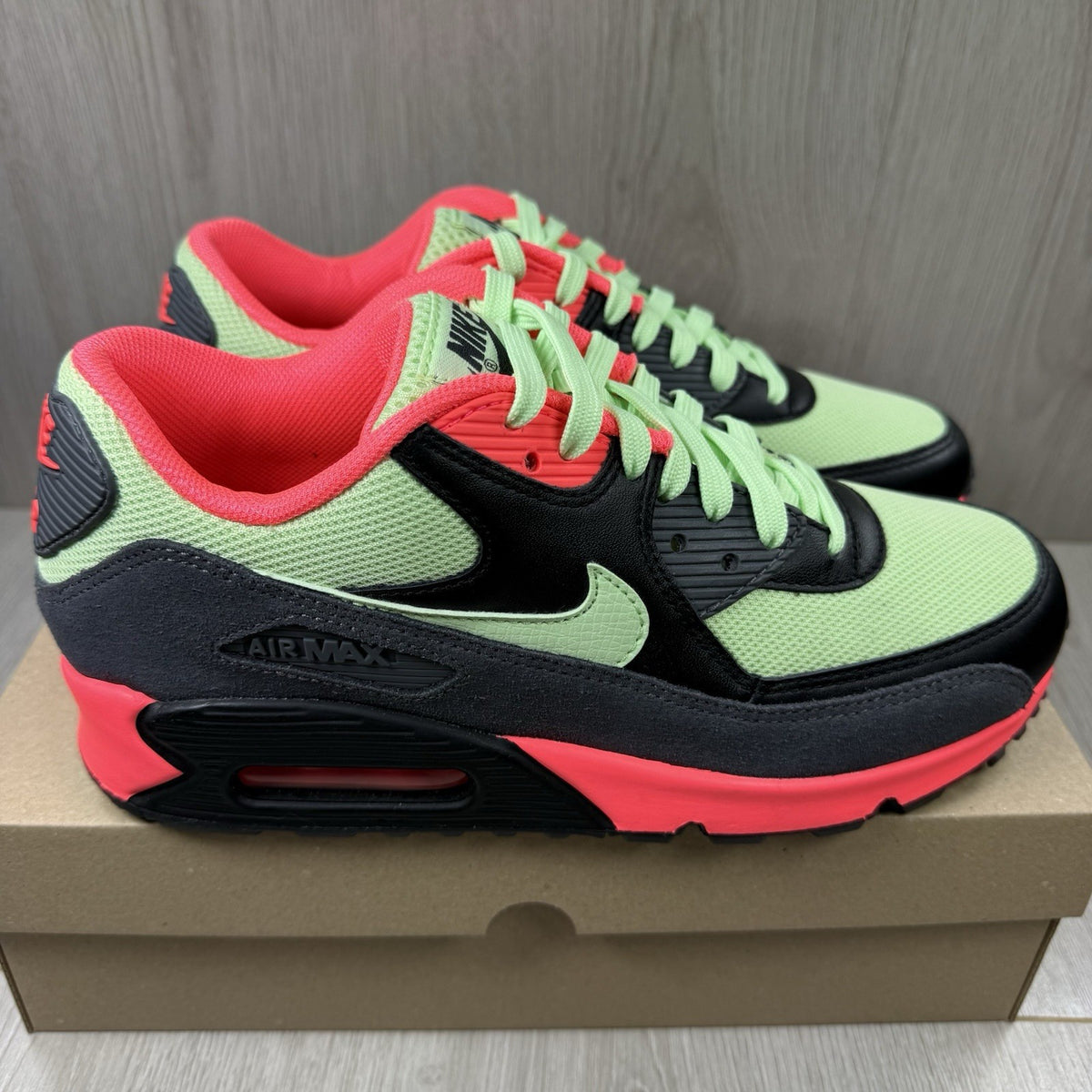 Nike Air Max 90 Essential green trainers with signature swoosh logo and mesh detailing.