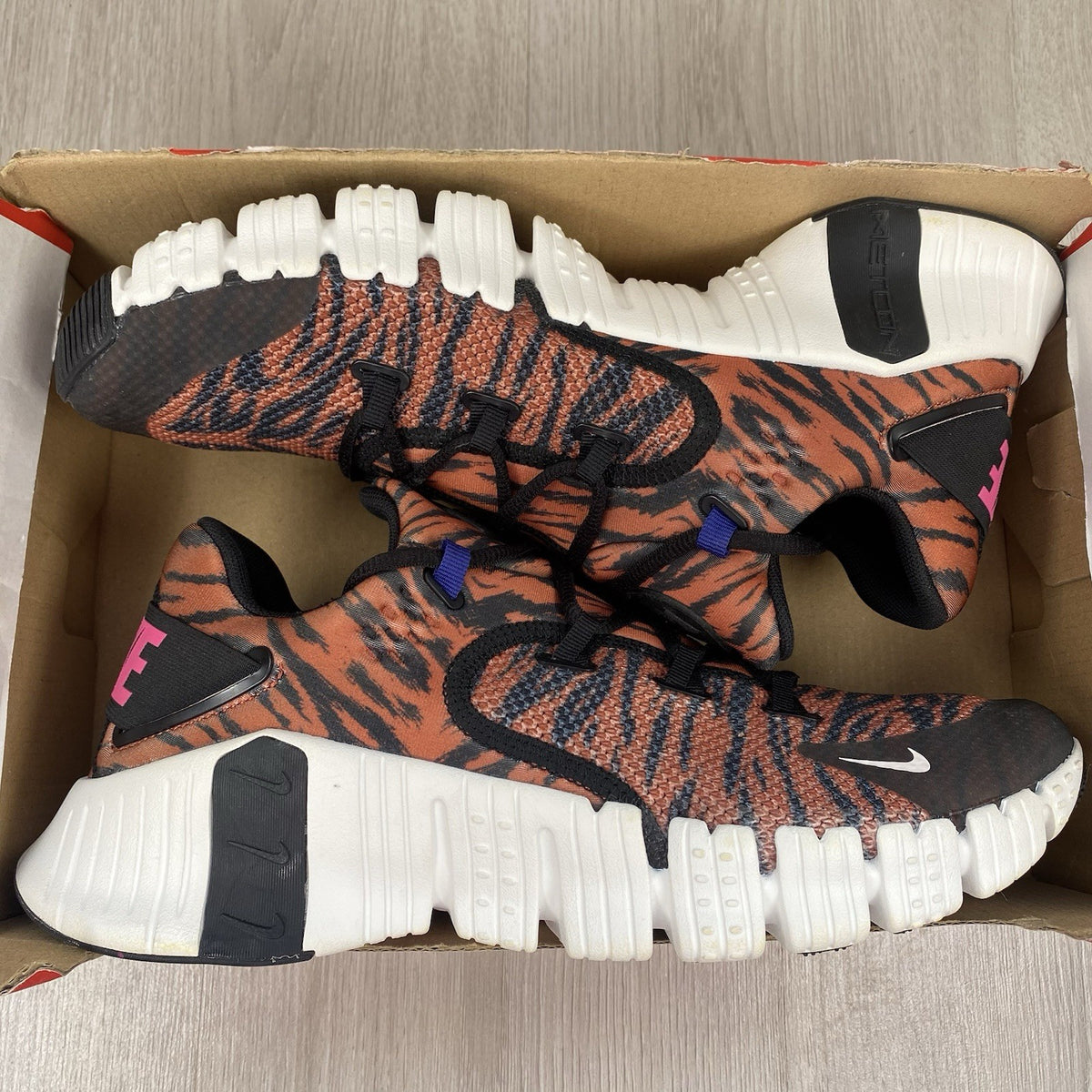Nike Free Metcon 4 trainers black with tiger burnt sunrise accents and logo detail.