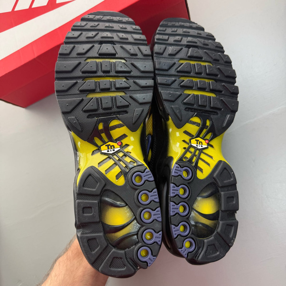 Nike black Air Max Plus TN trainers with bright citron accents and logo detail.