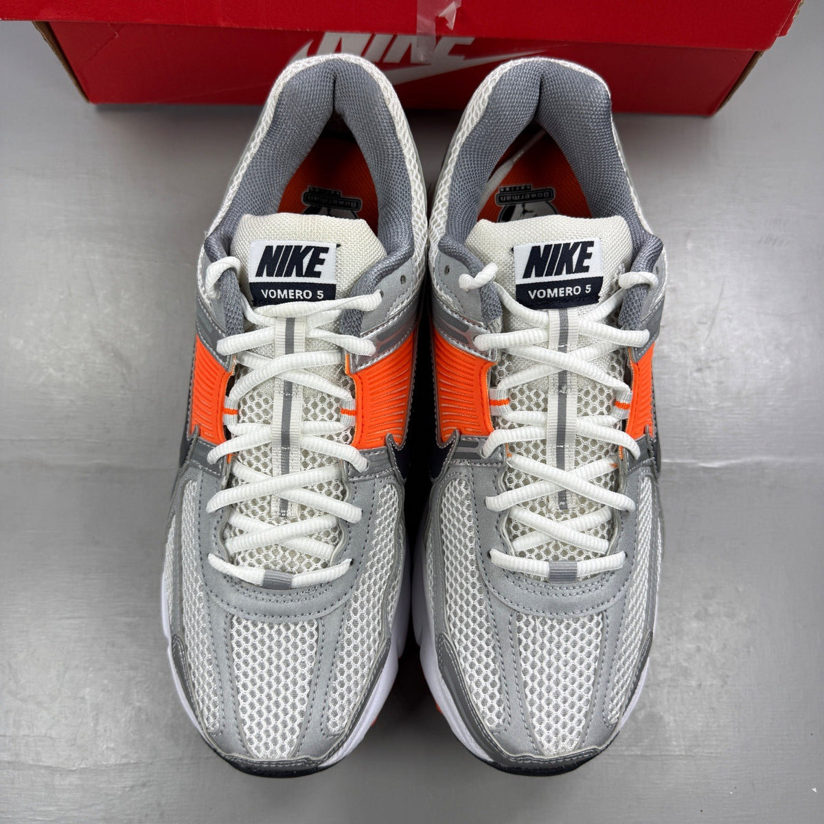 Nike running shoes orange with grey accents and distinctive logo detailing.