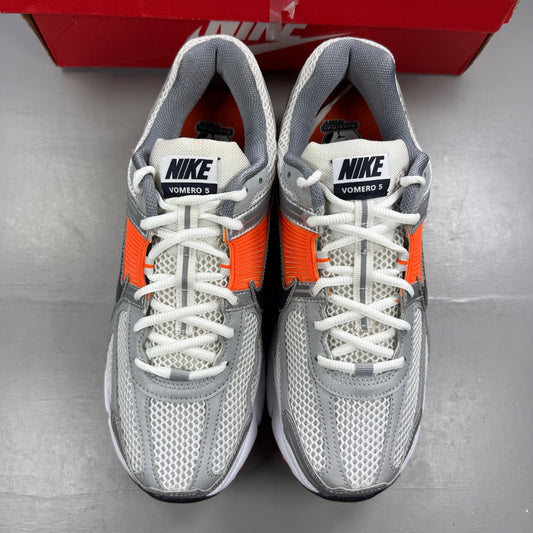 Nike running shoes orange with grey accents and distinctive logo detailing.