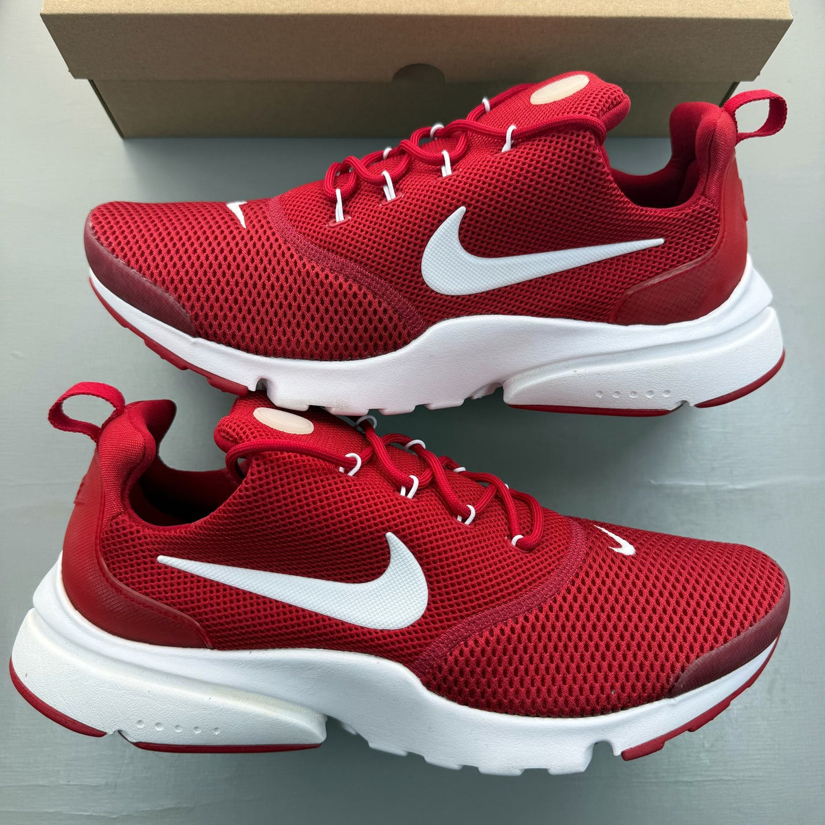 Nike Presto Fly red trainers with white accents and logo detail.