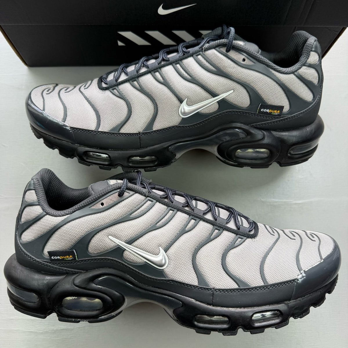 Nike black trainers with dark smoke grey accents and signature Air Max Plus design.
