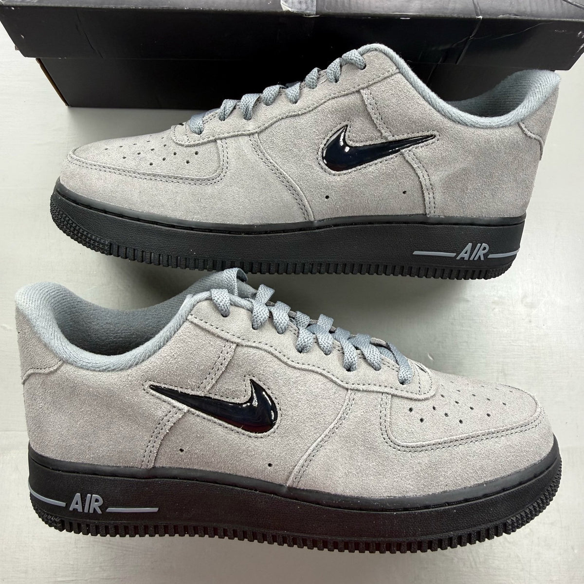 Nike Air Force 1 Low Jewel grey trainers with black accents and signature swoosh logo.