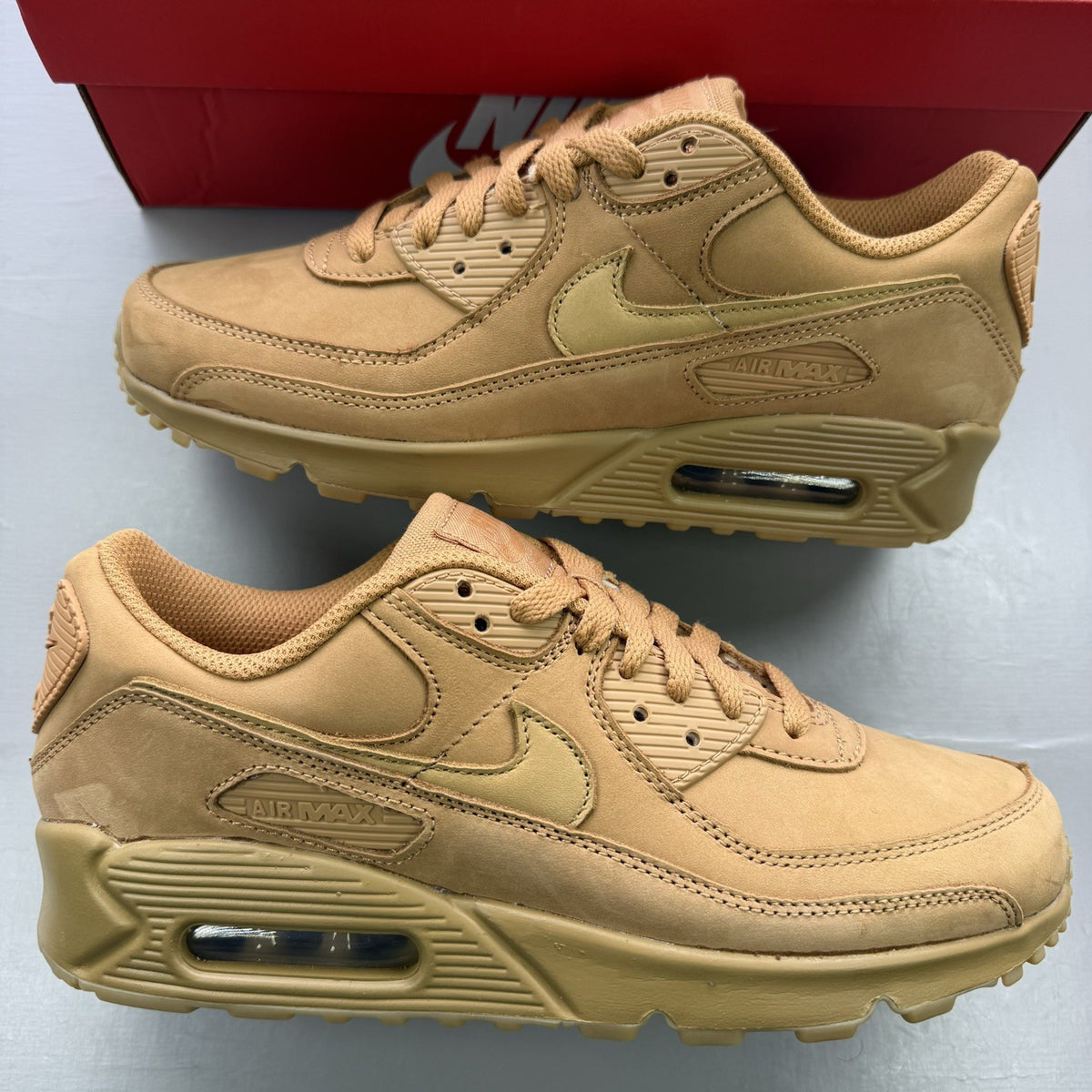 Nike Air Max 90 Premium beige trainers with gum sole and subtle branding details.