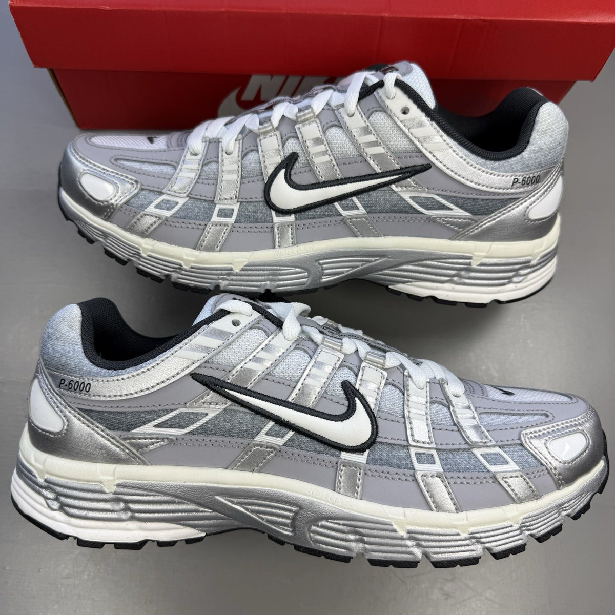 Nike P-6000 trainers metallic silver with white and grey accents, mesh material.