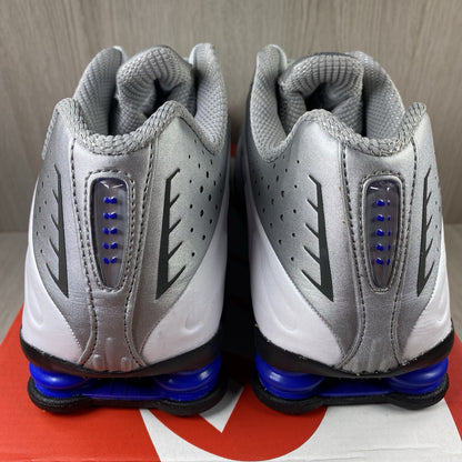 Nike Shox R4 trainers white with blue accents and distinctive Shox cushioning design.