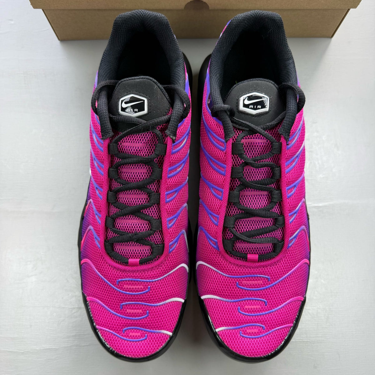Nike Air Max Plus TN pink and purple trainers with distinctive wave pattern and logo.