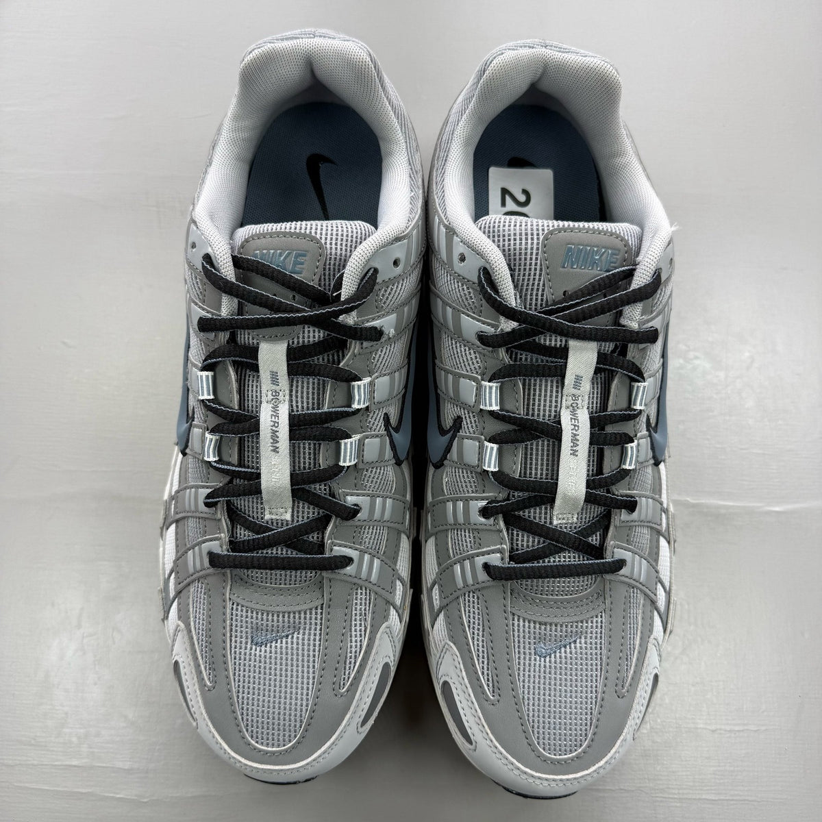 Nike grey trainers with blue accents and mesh material, featuring iconic swoosh logo.