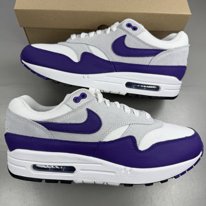 Nike Air Max 1 SC white trainers with purple and black accents, featuring logo detail.