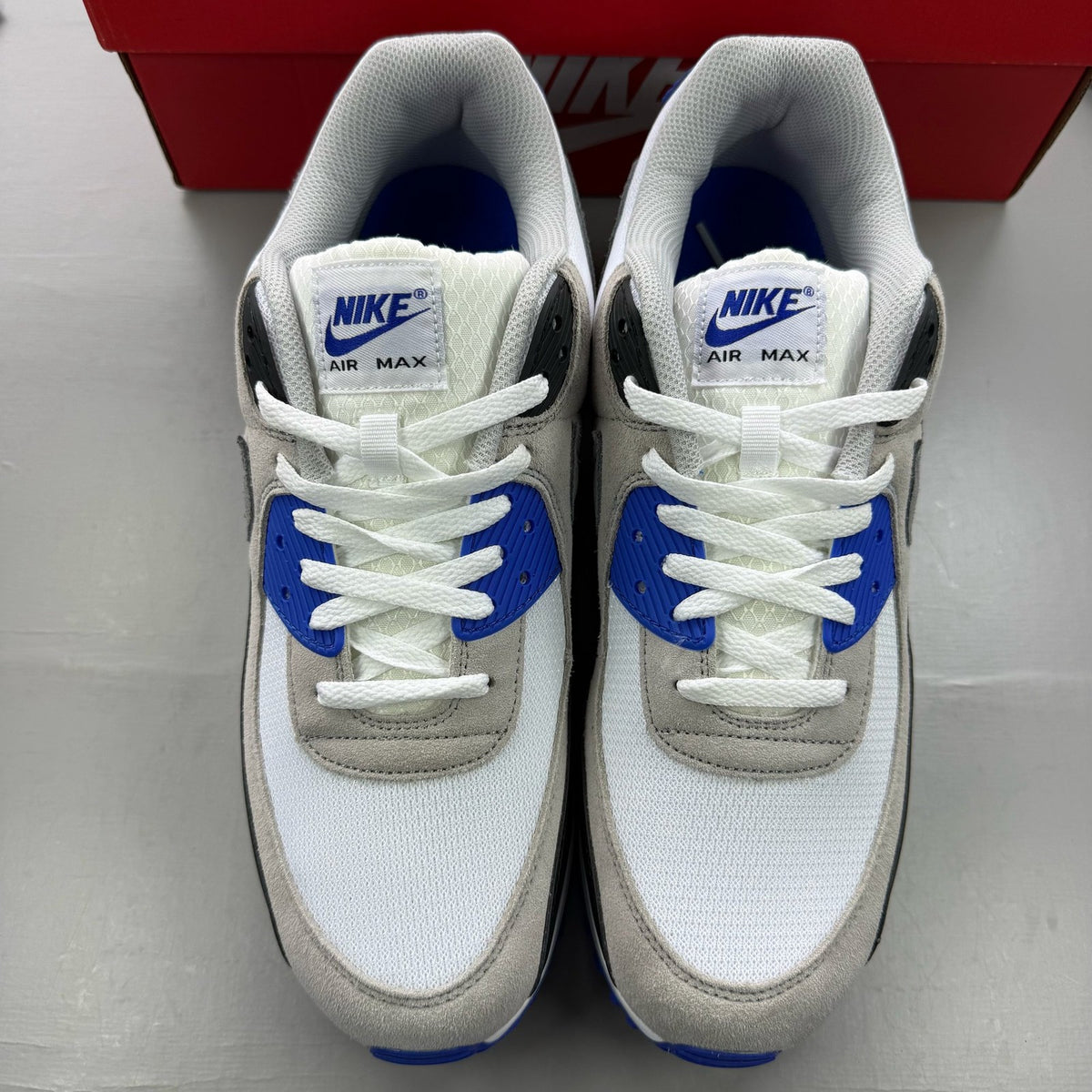Nike Air Max 90 trainers white grey blue with signature swoosh logo and mesh details.