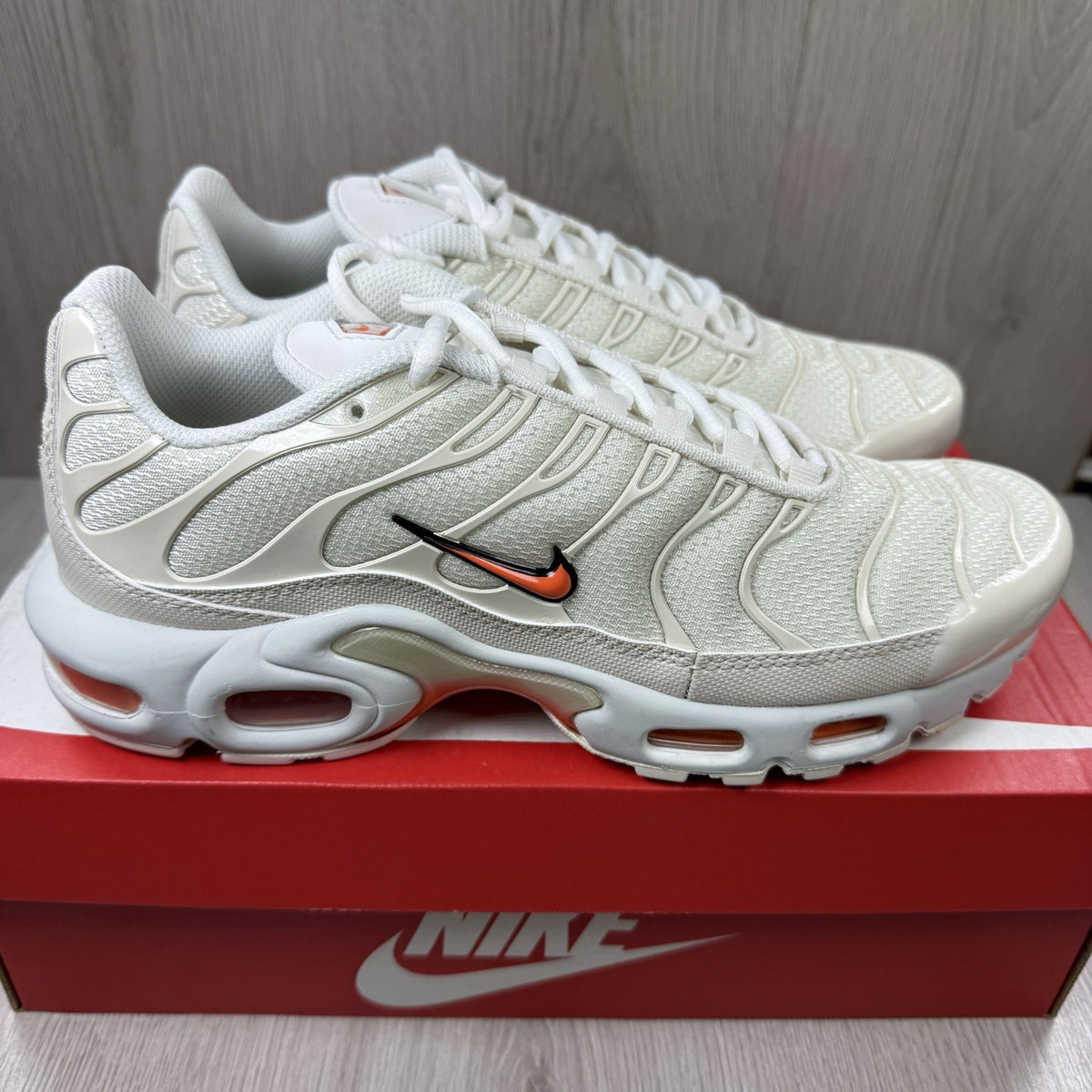 Nike Air Max Plus TN trainers in safety orange with distinctive wave pattern and logo.
