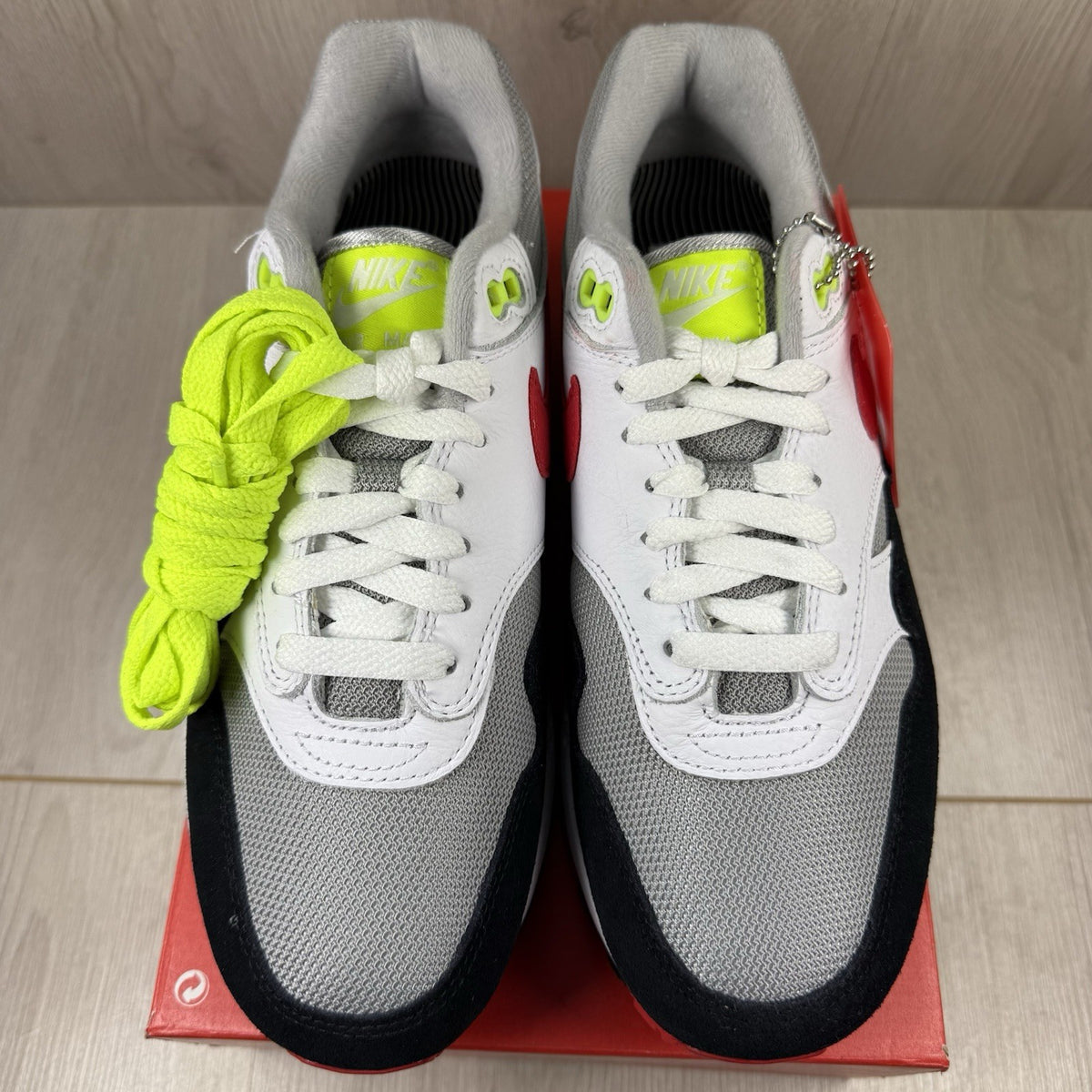 Nike Air Max 1 trainers white with chili volt accents and black detailing.