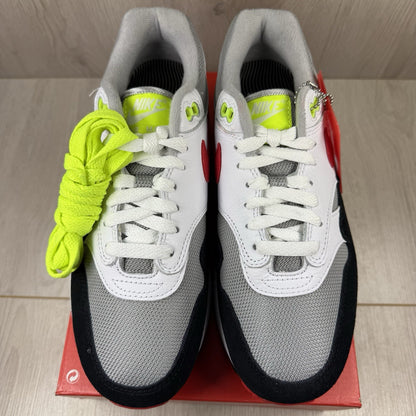 Nike Air Max 1 trainers white with chili volt accents and black detailing.
