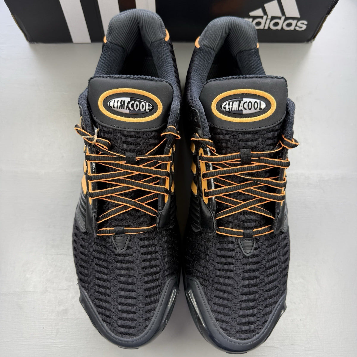 Adidas black trainers with flash orange accents and Climacool ventilation design.